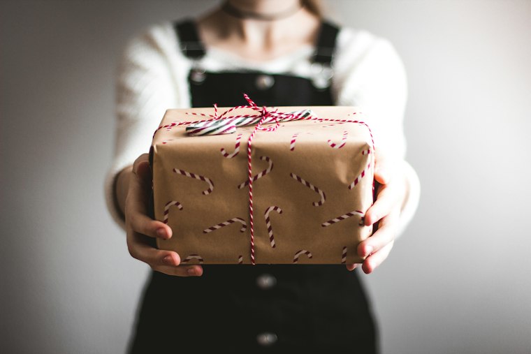 A wrapped kraft-paper gift being handed over with both hands