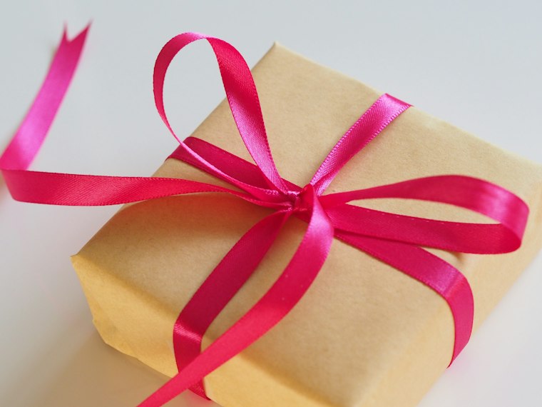 A small kraft gift box tied with a pink ribbon